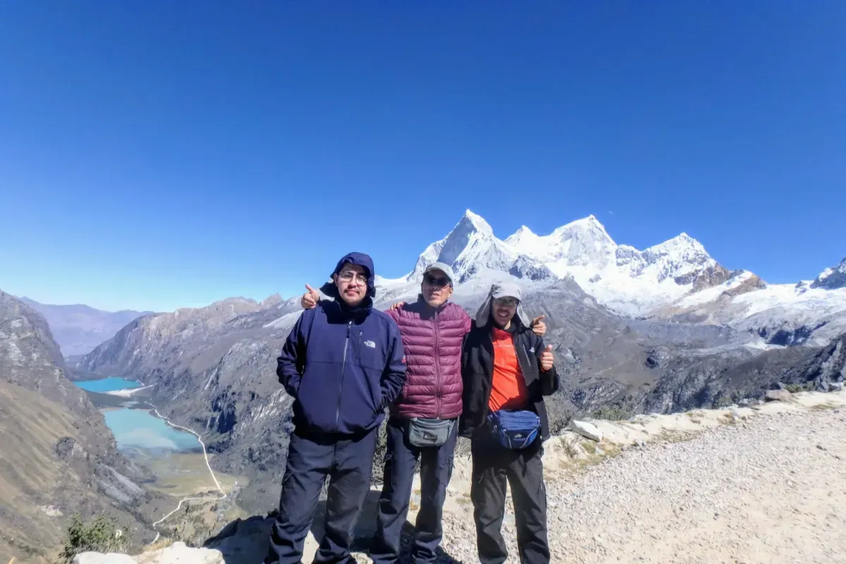 A group of trekkers at a viewpoint above a valley lake