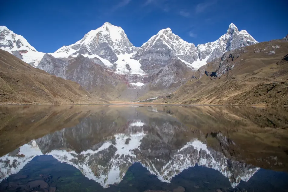 The Huayhuash peaks reflected in a mountain lake on a clear morning