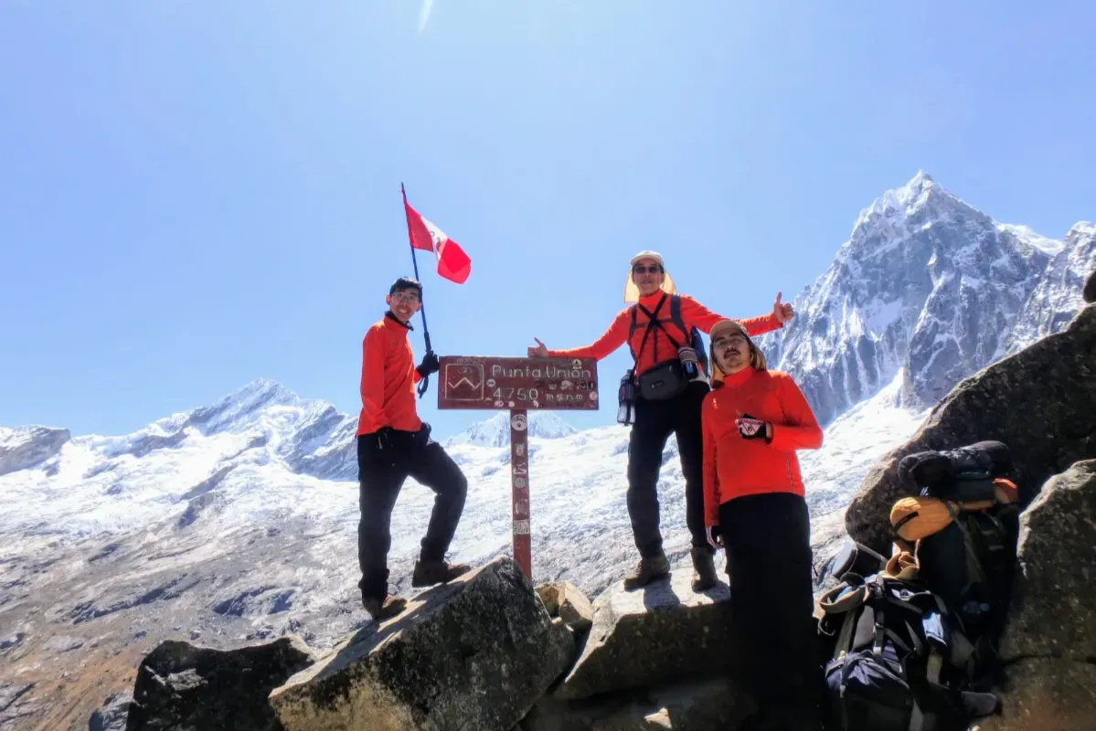 Trekkers celebrating at a high pass with the Peruvian flag