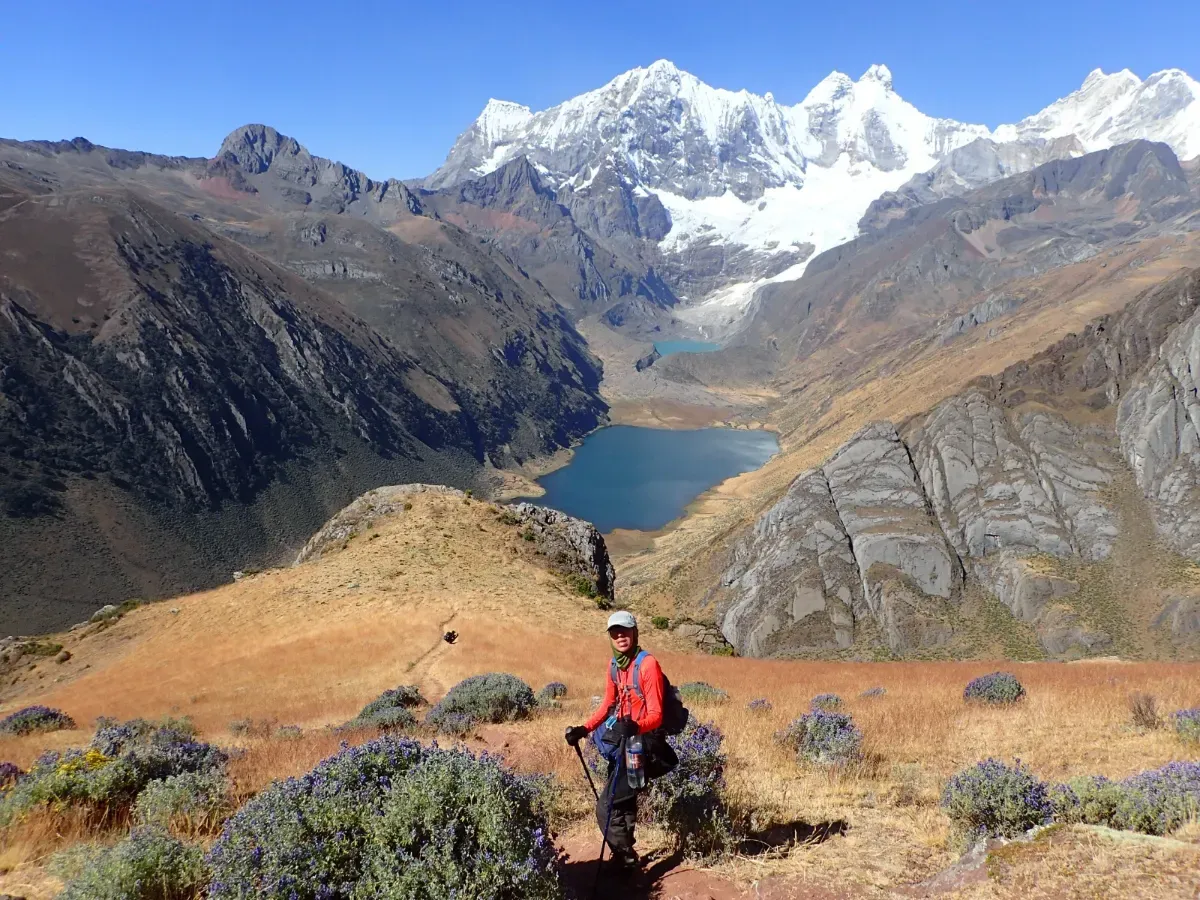 A trekker at a viewpoint above a deep-blue lake and glaciers